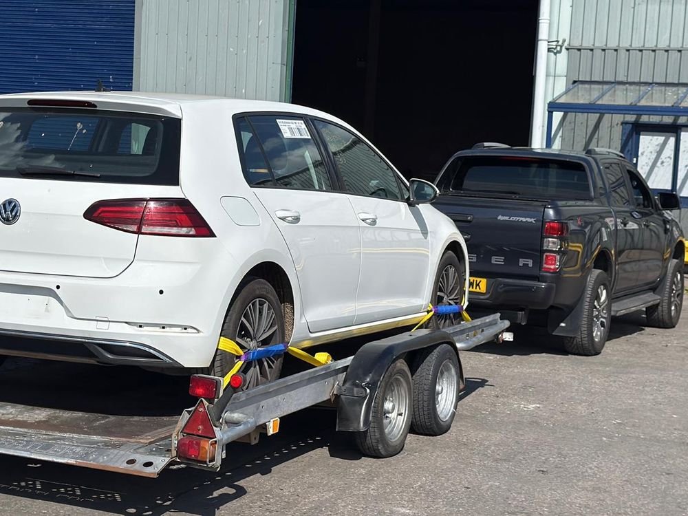 White Volkswagen Golf strapped onto a car trailer